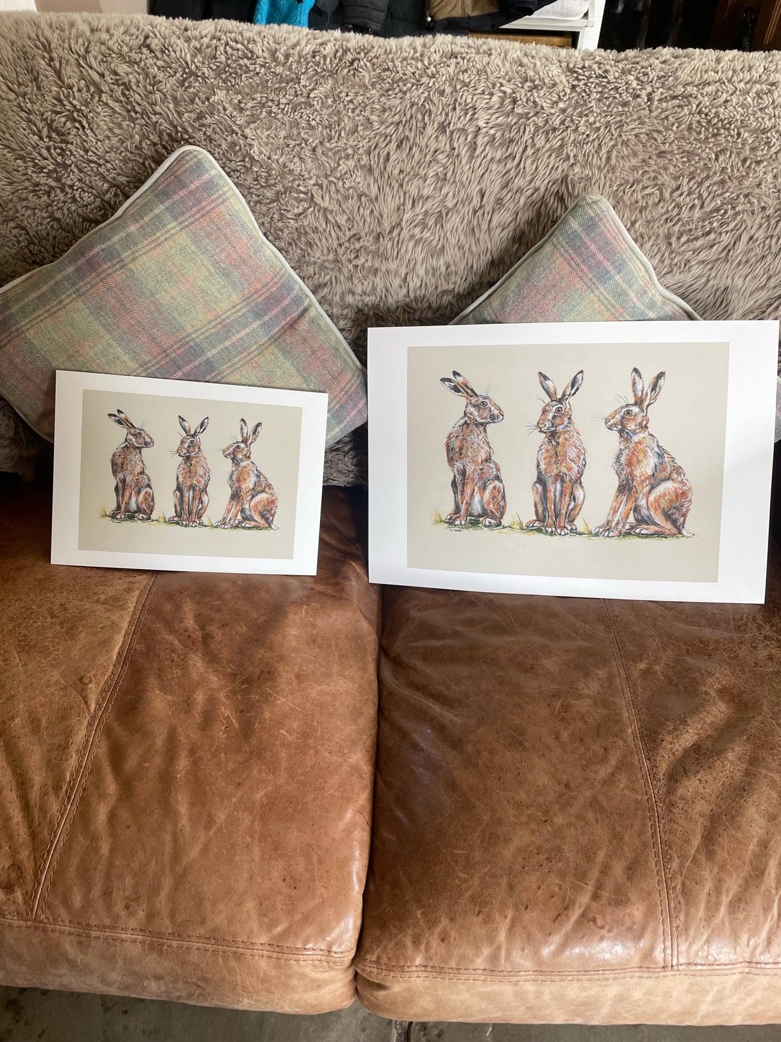 This print shows three hares together. The background is a neutral fawn colour