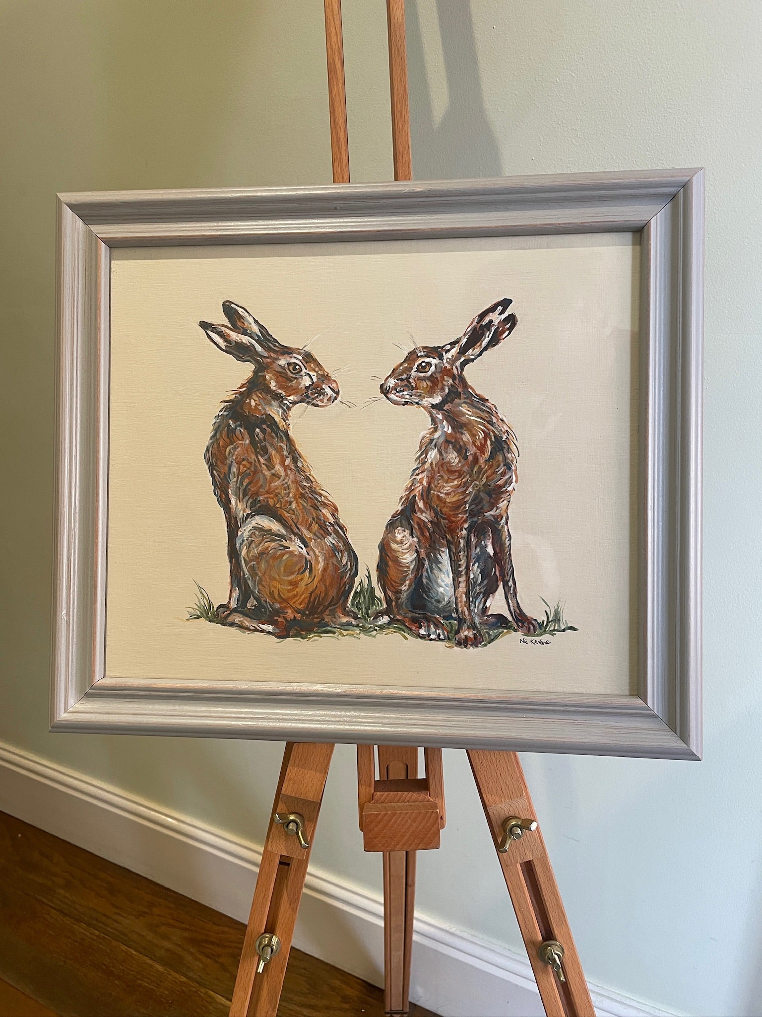 This painting features two hares in a heart shaped composition.   These characterful hares have been spied before they leap across the countryside meadow.