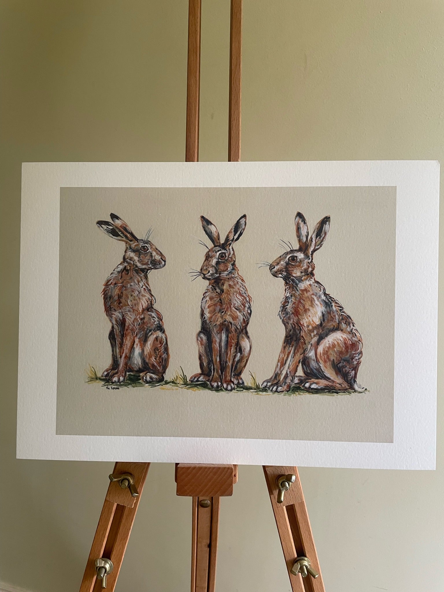 This print shows three hares together.  The background is a neutral fawn colour
